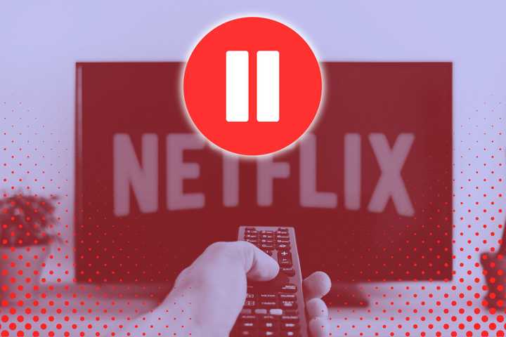 A person pointing a TV remote at a TV with Netflix on it. 