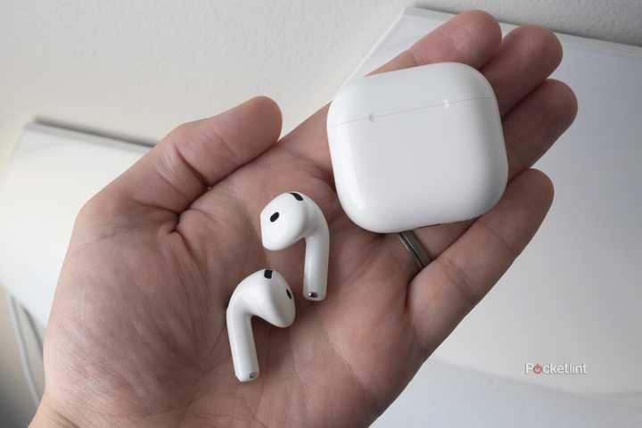 The AirPods 4 in a hand beside their case