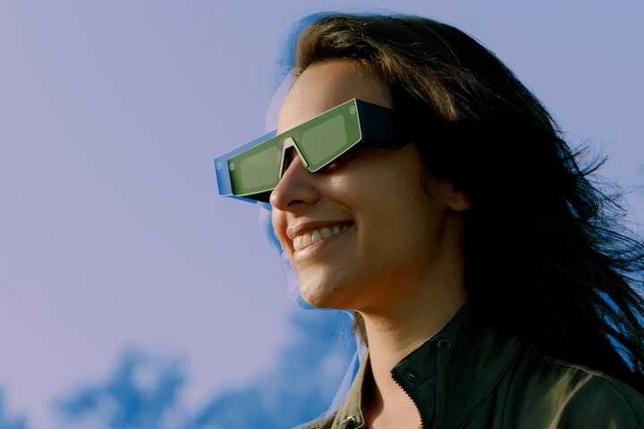 A person wearing Snap AR Spectacles outside and smiling.