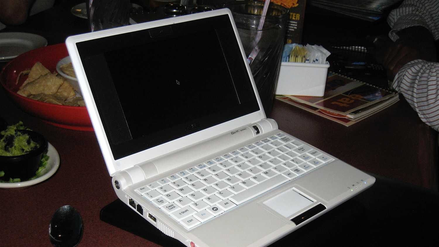A white Asus netbook sitting on a restaurant table.