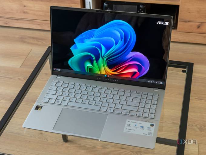 Angled view of the Asus Vivobook S 15 showinf the Windows 11 desktop on a glass table