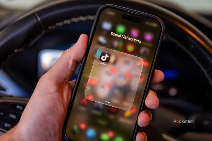 A still photo of a driver holding their phone with the TikTok app displayed. 