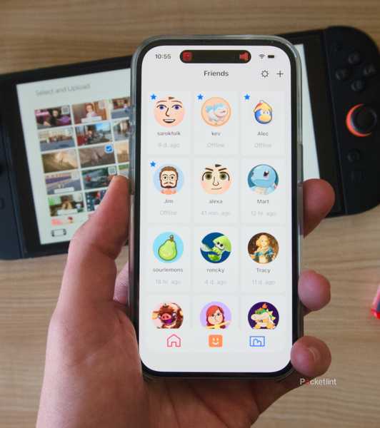 A hand holding an iPhone displaying the friends list in the Nintendo Switch App.