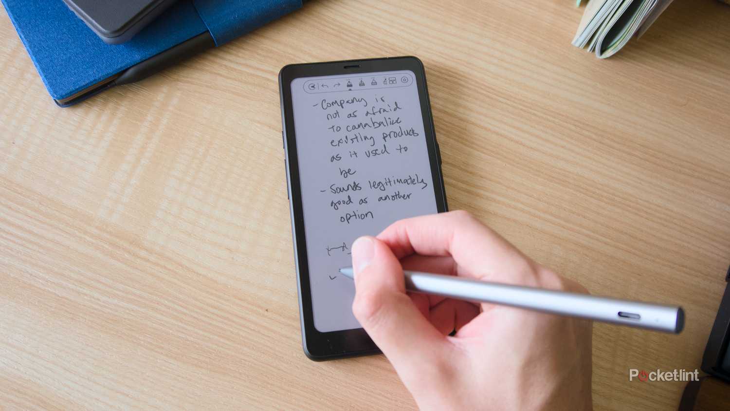 A hand using the InkSense Plus stylus to write on the Palma 2 Pro.