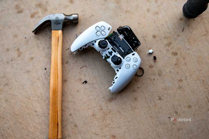 A still photo of a smashed Playstation 5 controller next to a hammer. 