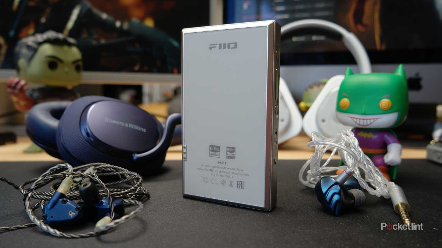 FiiO M21 showing the Anti-Glare frosted back glass, with various headphones and IEMs next to it
