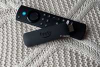 Fire TV Stick and remote on knitted pillow.
