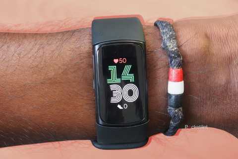 A black Fitbit Charge 6 on a orange background.