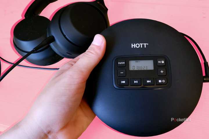 Hott CD204 being held above a wooden desk with over-ear headphones plugged in