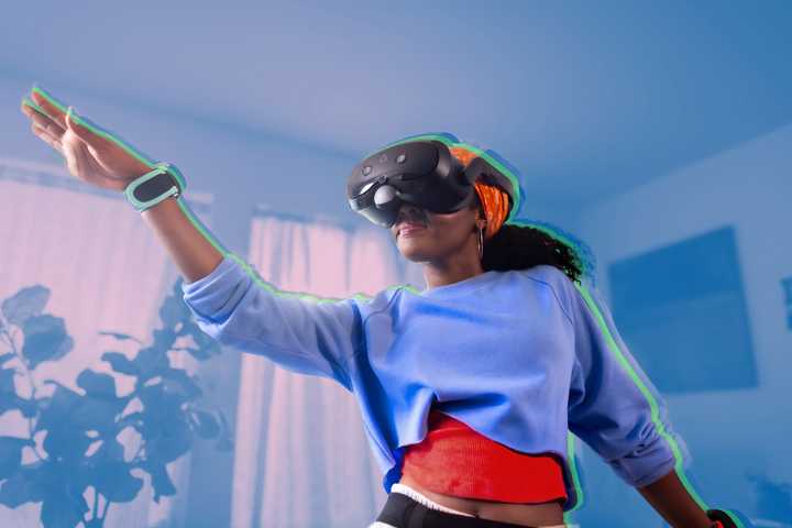 A woman wearing a Vive Focus Vision headset and dancing with motion trackers trapped to her arms.