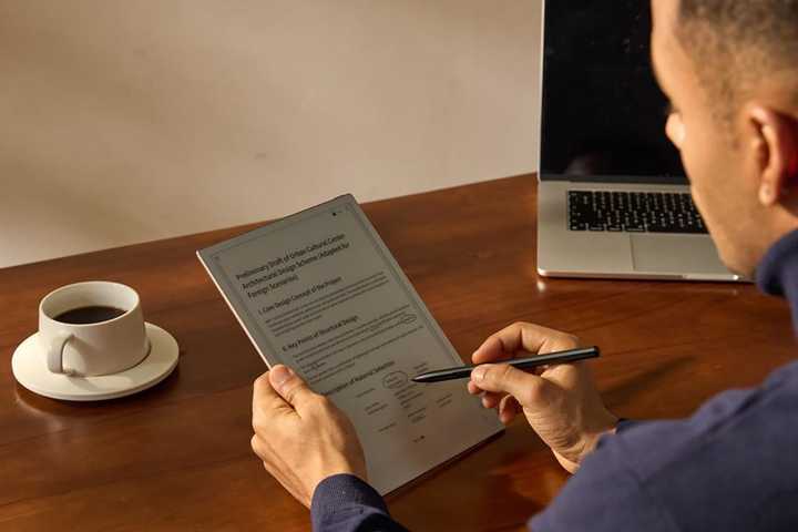 The iFlyTek AINOTE 2 E-ink tablet and smartpen in someone's hands.