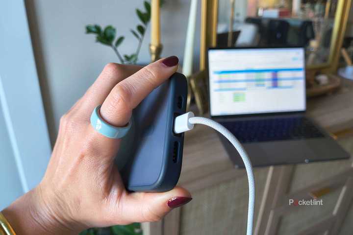 A hand holding an iPhone 16 Pro plugged in. 