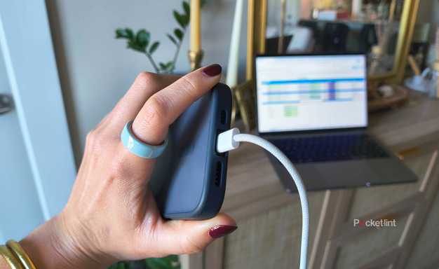 A hand holding an iPhone 16 Pro plugged in. 