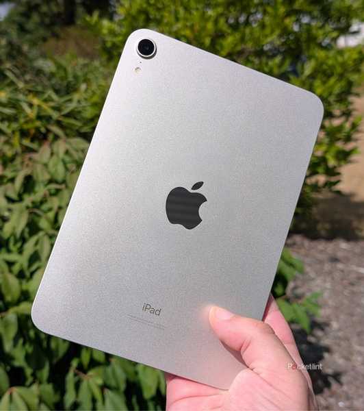 An iPad mini being held up in the air.