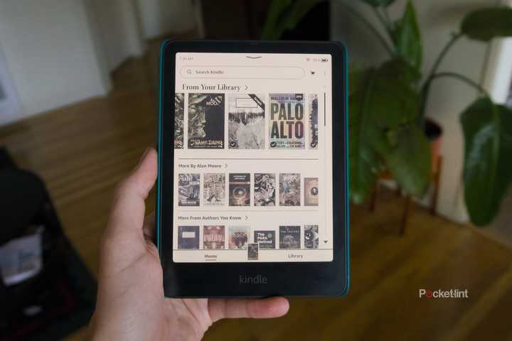 A hand holding a Kindle Colorsoft open to its home screen.