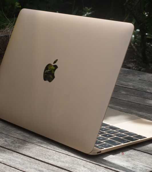 A gold 12-inch MacBook outside on a wooden table.