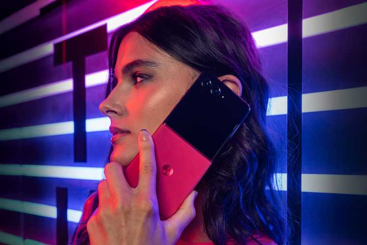 Motorola Razr+ in hand in dark red lighting. 