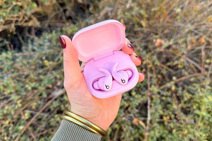 Holding the Pink Powerbeats Fit. 