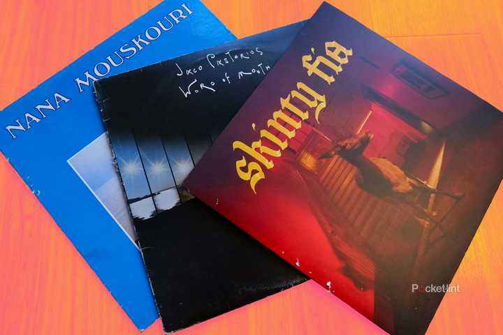 Three records in their jackets on a wooden floor, from left to right: Nana Mouskouri's Athina, Jaco Pastorius' Word of Mouth, and Fontaines DC's Skinty Fia.