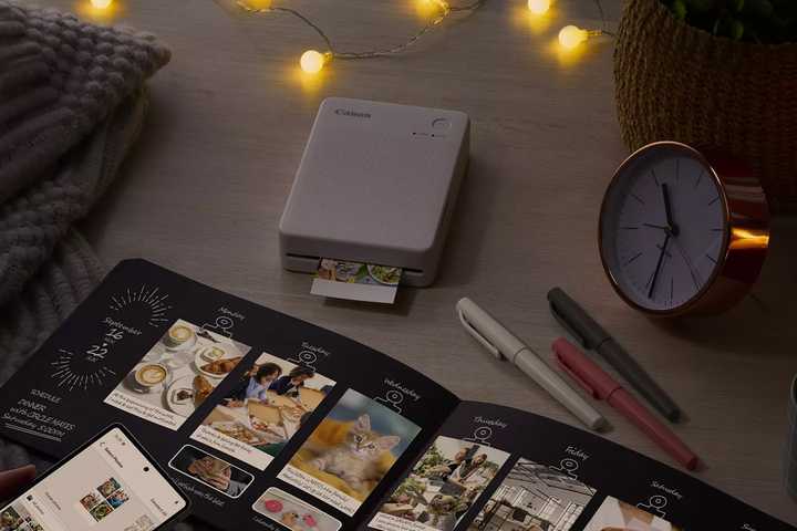The Canon Selphy QX20 sits on a table with scrapbooking materials