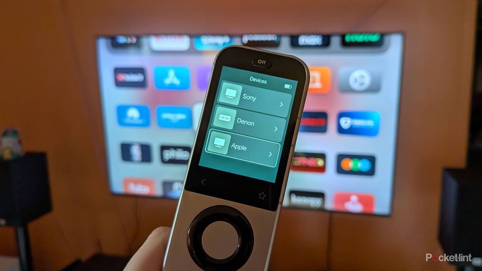 A Sofabaton X2 remote in front of a TV.