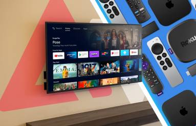 A smart TV mounted to a wall with a Google TV splash screen alongside various streaming boxes