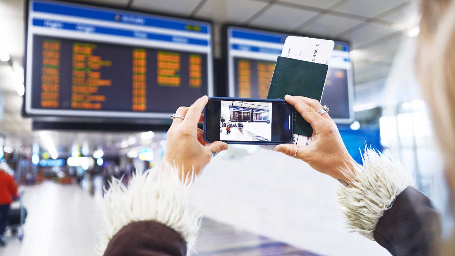 woman taking a photo of departure information - yesim