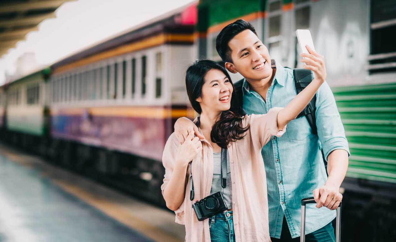 couple taking a selfie beside a train - yesim
