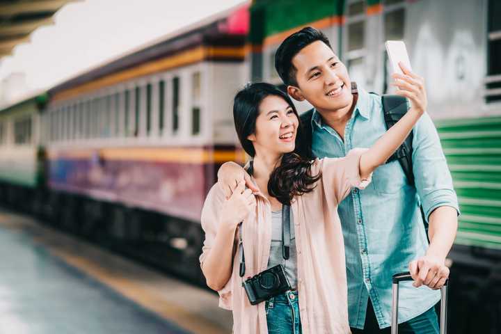 couple taking a selfie beside a train - yesim
