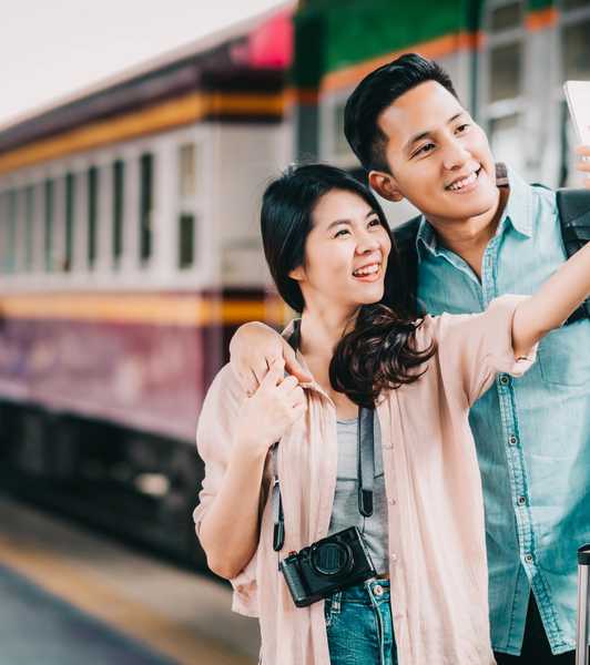 couple taking a selfie beside a train - yesim